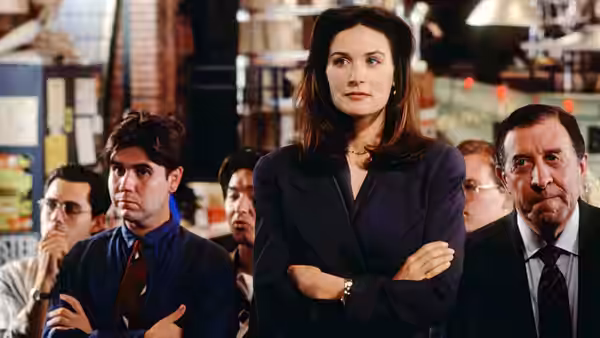 Meredith Johnson stands with folded arms among colleagues in a crowded office