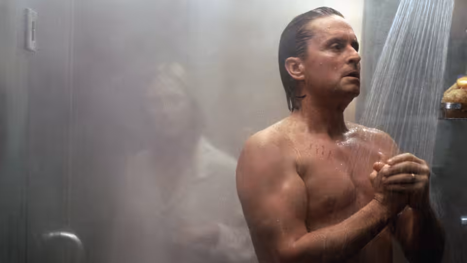 Tom Sanders (Michael Douglas) stands under a shower, clutching his hands to his chest