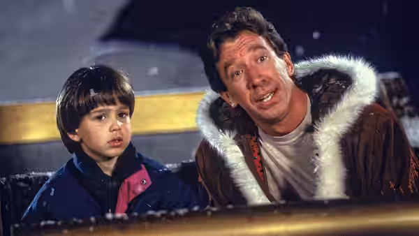 Scott Calvin (Tim Allen) and Charlie (Eric Lloyd) lean over a railing as snow falls