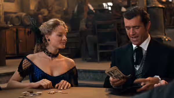 Annabelle Bransford (Jodie Foster) watches Bret Maverick (Mel Gibson) examine a banknote at a poker table