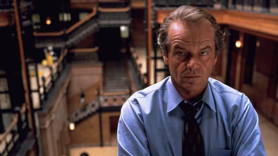 Will Randall (Jack Nicholson) sits in his office wearing a blue shirt and tie