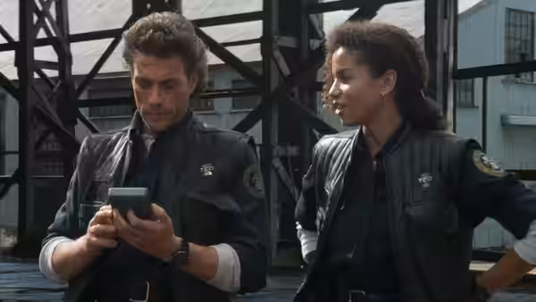 Max Walker (Jean-Claude Van Damme) checks a device beside Fielding (Gloria Reuben) outdoors