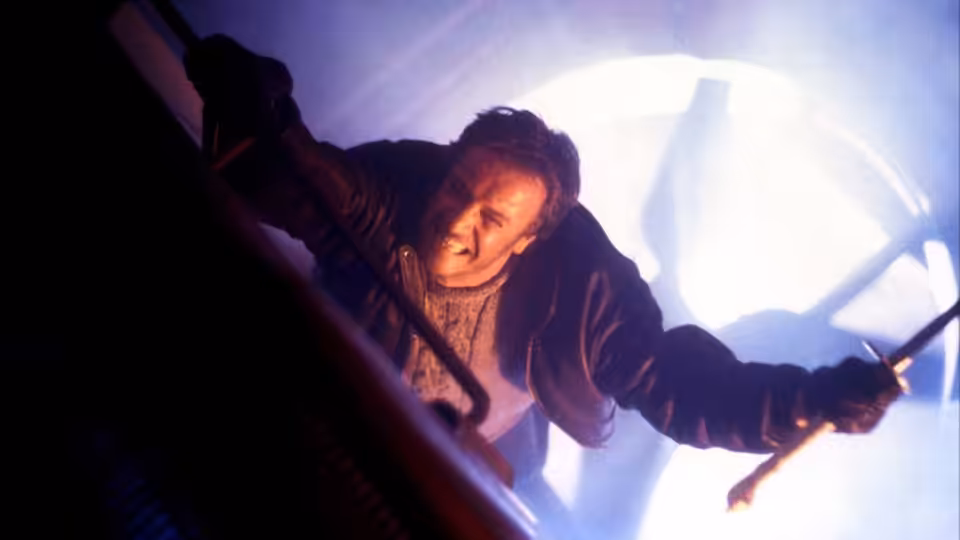 Connor MacLeod (Christopher Lambert) reaches forward with a sword amid a bright burst of light