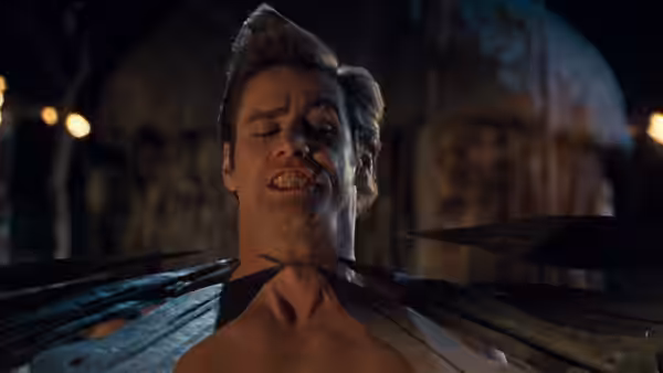 Ace Ventura (Jim Carrey) grimaces as spears point toward his neck