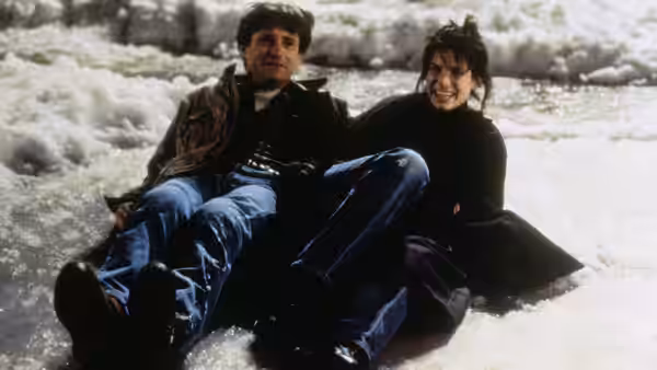 Lucy (Sandra Bullock) and Jack (Bill Pullman) sit together in rushing river water