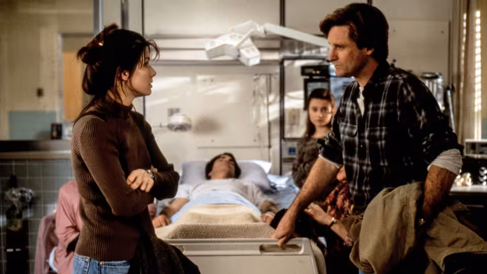 Lucy (Sandra Bullock) and Jack (Bill Pullman) stand beside Peter's hospital bed