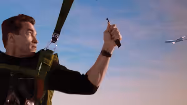 Eraser (Arnold Schwarzenegger) hangs from a parachute harness and raises a small object toward an aircraft