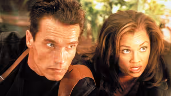 Eraser (Arnold Schwarzenegger) and Lee (Vanessa Williams) crouch together, looking offscreen