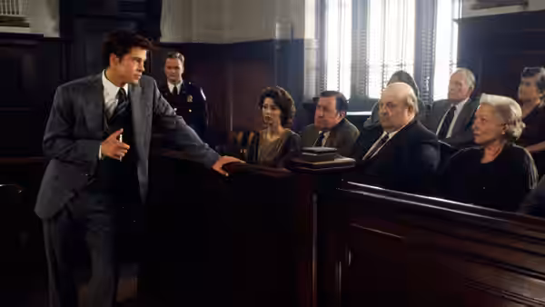 A lawyer addresses the courtroom while the defendant and spectators watch from the benches