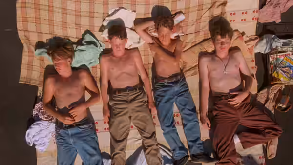 Four shirtless boys lie bruised on a room's floor