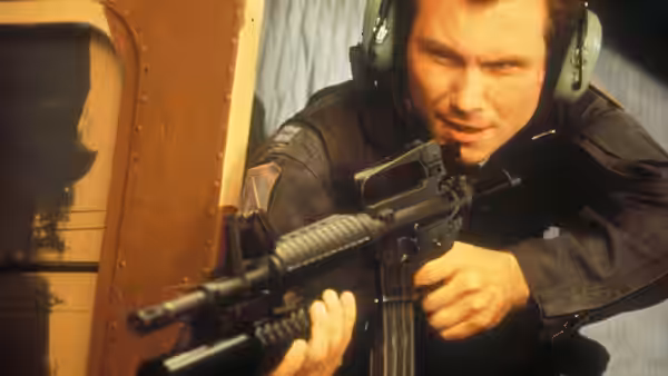 Riley Hale (Christian Slater) crouches with a rifle beside an aircraft doorway