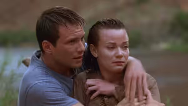 Riley Hale (Christian Slater) holds a distressed Terry Carmichael (Samantha Mathis) beside a river
