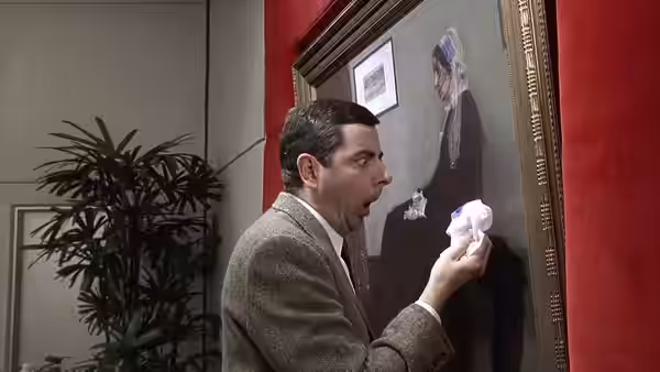 Mr. Bean (Rowan Atkinson) holds a tissue beside a framed painting in a gallery