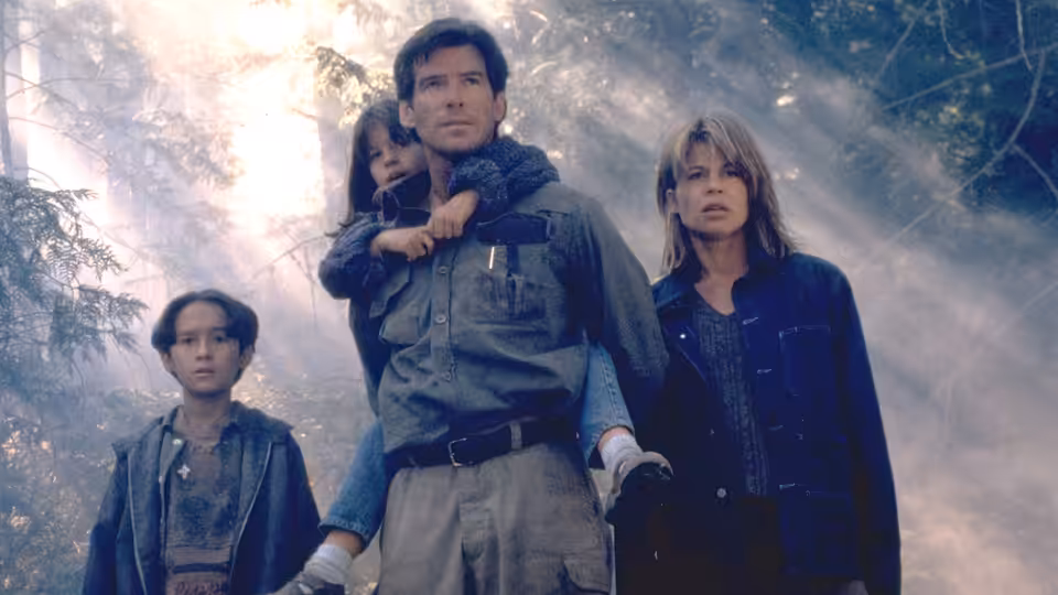 Harry Dalton (Pierce Brosnan), Rachel Wando (Linda Hamilton), and the children move through smoky woods