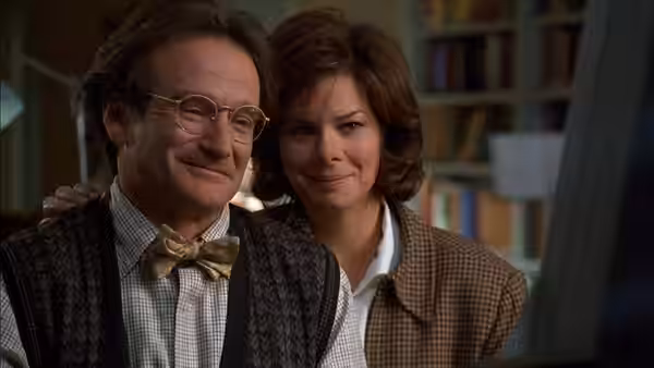 Professor Philip Brainard (Robin Williams) and Dr. Sara Jean Reynolds (Marcia Gay Harden) smile together indoors