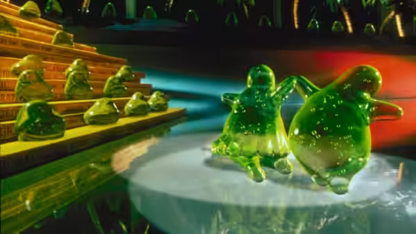 Green blobs bounce across a table beside rows of miniature green figures