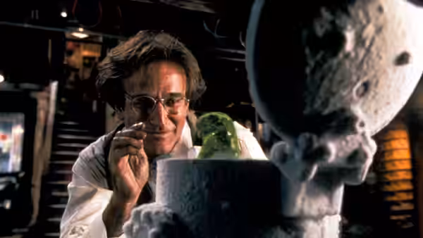 Professor Philip Brainard (Robin Williams) examines a green blob beside a moon model in his laboratory