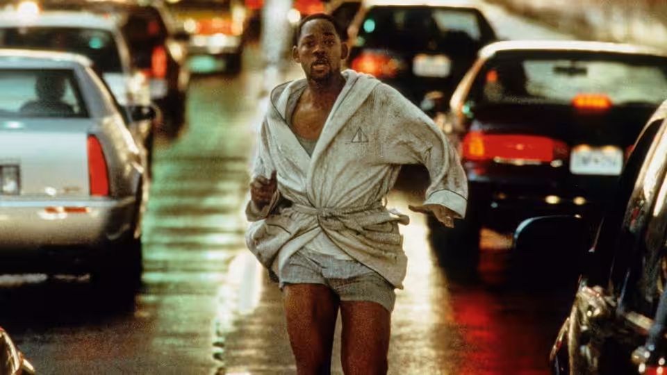 Robert Clayton Dean (Will Smith) runs through traffic on a rain-soaked city street