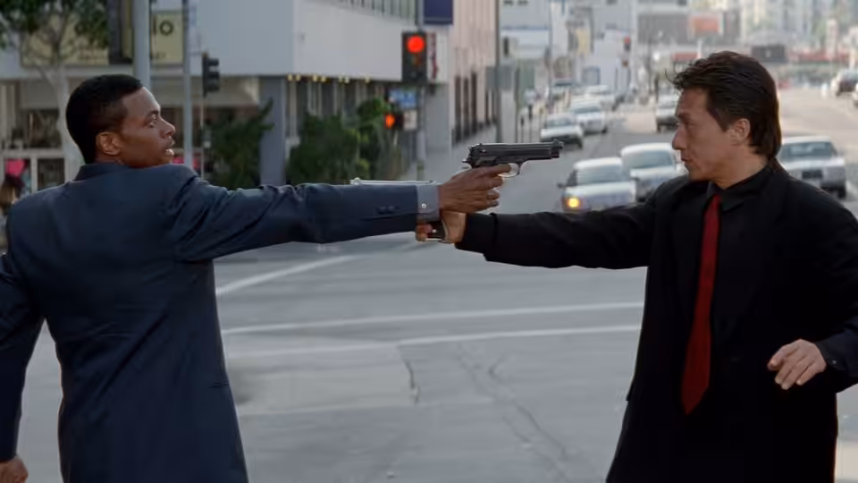 Carter (Chris Tucker) points a gun at Lee (Jackie Chan) in a city intersection
