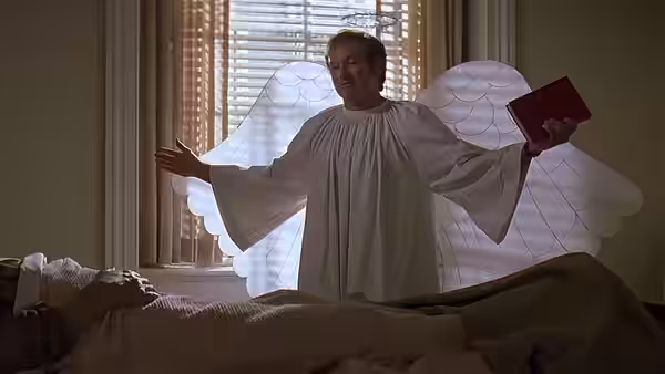 Patch Adams (Robin Williams) wears angel wings and a white robe beside a patient in bed