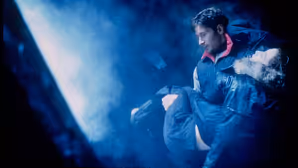 Fox Mulder (David Duchovny) carries an unconscious person through a blue-lit passage