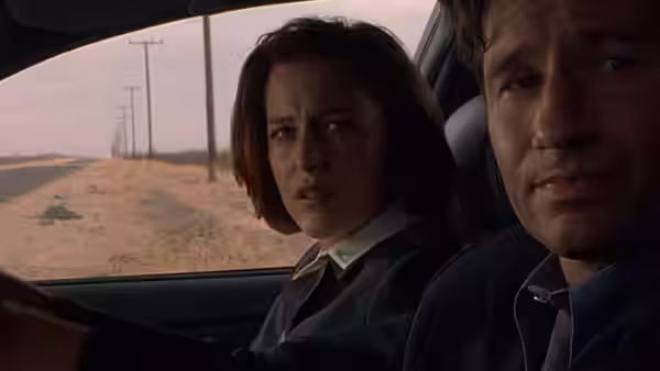 Dana Scully (Gillian Anderson) and Fox Mulder (David Duchovny) sit inside a car