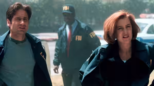Fox Mulder (David Duchovny) and Dana Scully (Gillian Anderson) approach as an FBI agent follows