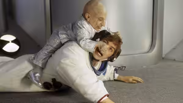 Mini-Me clings to Austin Powers and wrestles him to the floor