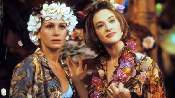 Maggie Carpenter (Julia Roberts) and Peggy Flemming (Joan Cusack) wear flower crowns and leis indoors