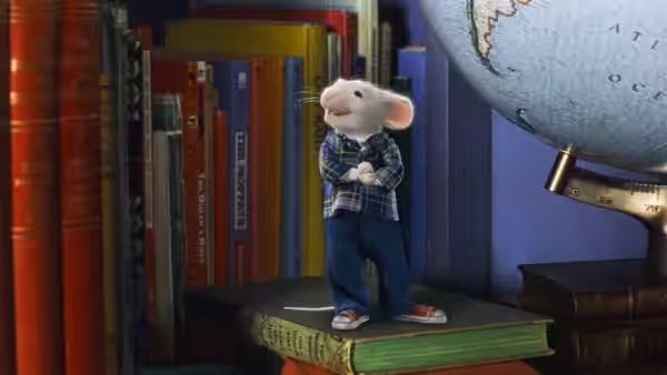 Stuart Little stands on a stack of books beside a globe in the library