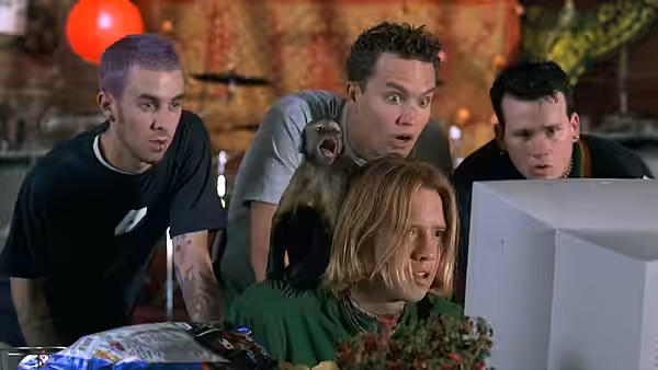 Several young men and a small monkey stare wide-eyed at a computer monitor