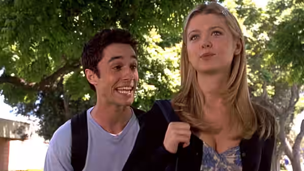 Kevin Meyers (Thomas Ian Nicholas) walks beside a blonde young woman beneath leafy trees