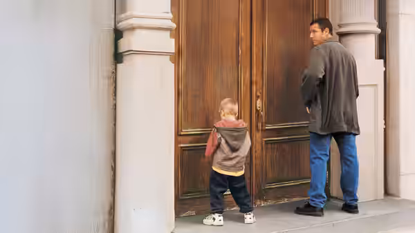 Sonny and Julian face a large wooden doorway on a city street