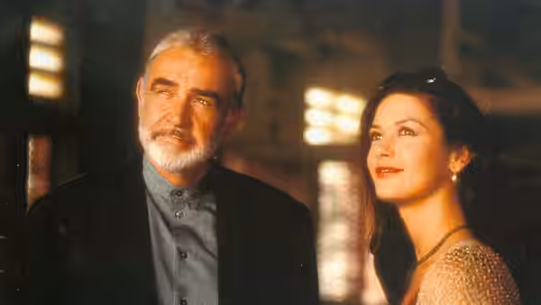 Mac (Sean Connery) and Gin Baker (Catherine Zeta-Jones) stand together inside a warmly lit room