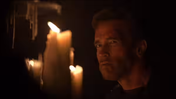 Jericho Cane (Arnold Schwarzenegger) watches from beside a cluster of candles