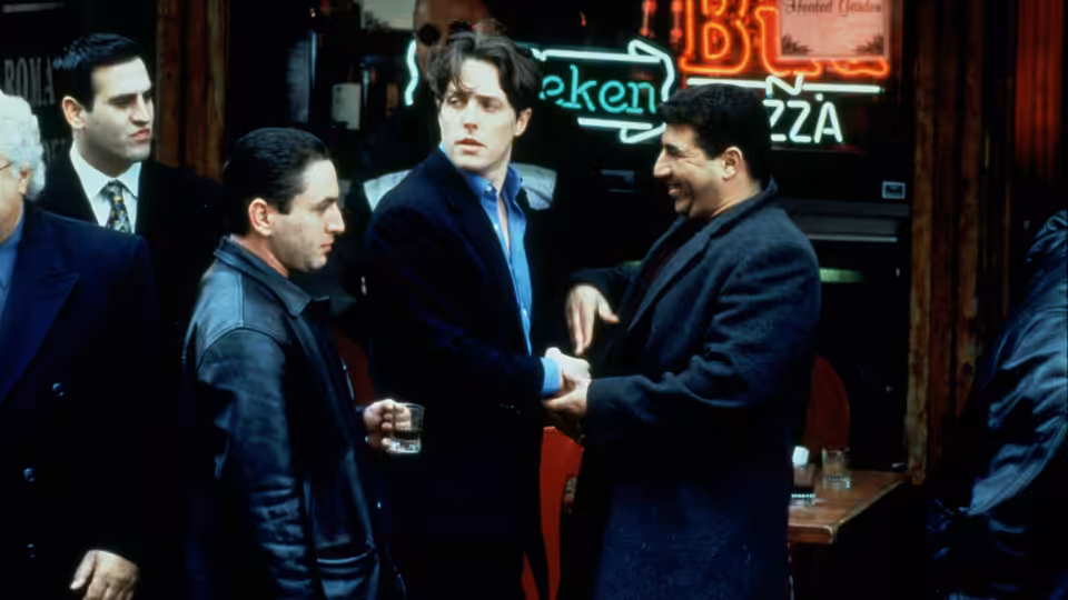 Michael Felgate (Hugh Grant) talks with Frank Vitale (James Caan) and other men outside a bar