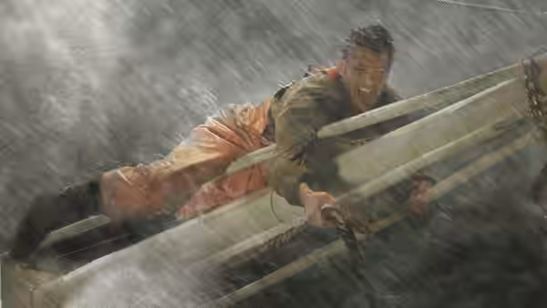 A fisherman in orange waterproofs clings to the rail of a boat in driving rain