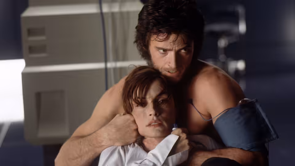Logan (Hugh Jackman) holds Jean Grey (Famke Janssen) protectively in a laboratory