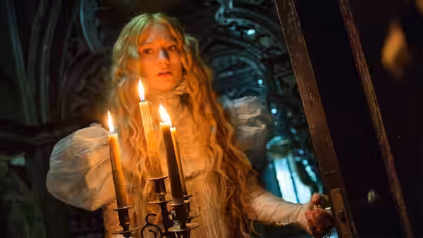 Edith Cushing holds a candle as she opens a door in the mansion