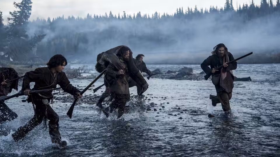 Group of men wading through a shallow river carrying rifles