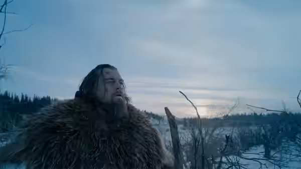 Hugh Glass (Leonardo DiCaprio) standing in snowy landscape at dusk