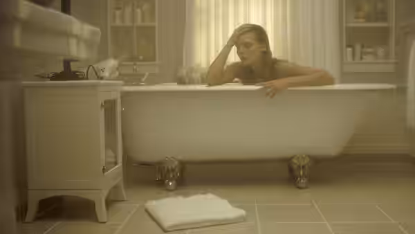 Claire Spencer (Michelle Pfeiffer) leans over the edge of a bathtub in her bathroom
