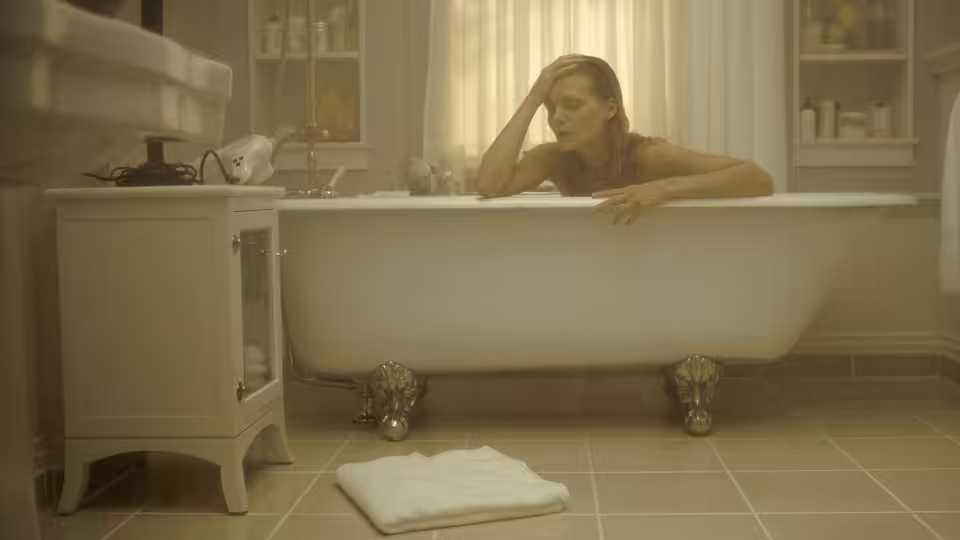 Claire Spencer (Michelle Pfeiffer) leans over the edge of a bathtub in her bathroom