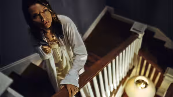 Claire Spencer (Michelle Pfeiffer) grips the banister on a staircase and looks upward