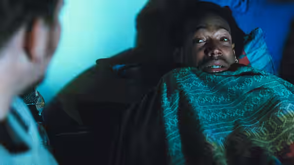 Shorty (Marlon Wayans) lies beneath a blanket, staring fearfully at someone beside the bed