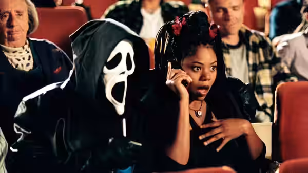 Brenda (Regina Hall) talks on a phone beside a masked figure in a theater