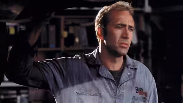 Memphis Raines (Nicolas Cage) raises an arm beneath a car in the garage