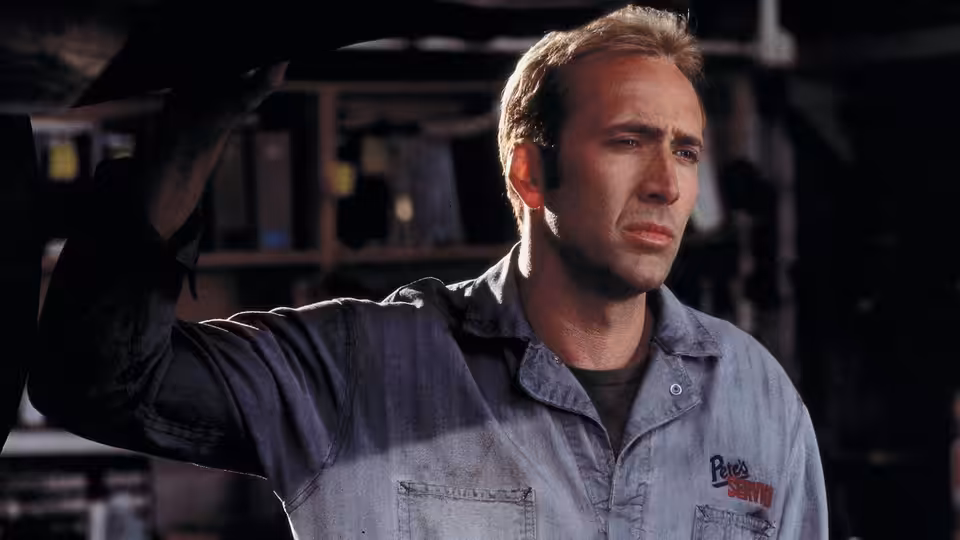 Memphis Raines (Nicolas Cage) raises an arm beneath a car in the garage