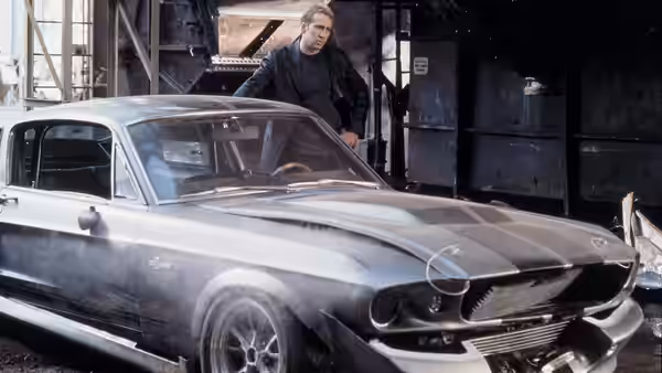 Memphis Raines (Nicolas Cage) stands beside a silver Mustang in a workshop