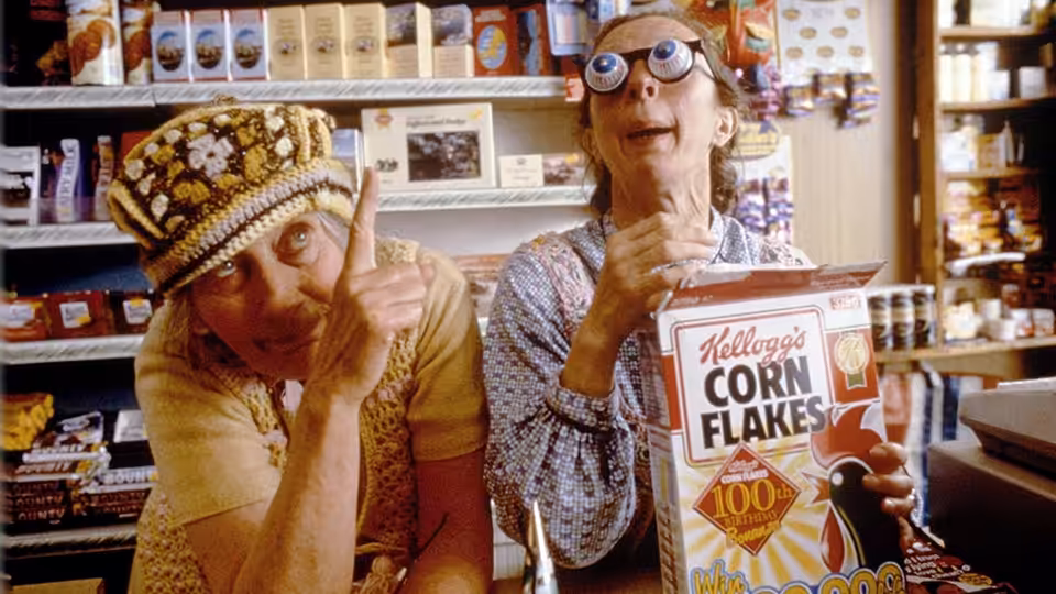 Two shoppers wear novelty disguises beside a cereal box in a grocery aisle
